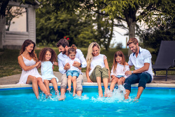 Large group of people sitting by the swimming pool.