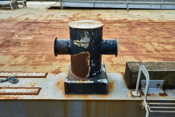 A cruciform mooring bollard showing signs of wear from rope and chains