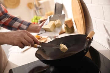 Man putting butter into frying pan, closeup