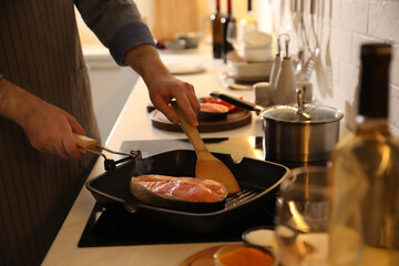 Man cooking fresh salmon steak in frying pan, closeup