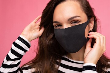 Shot of young attractive woman wearing mediacal face mask isolated over background wall. Protection against COVID-19