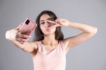 Naklejka premium woman taking selfie and making victory sign