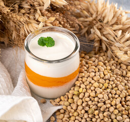 Non-dairy alternatives Soy milk or yogurt with mango in jar on white table with soybeans and cereal
