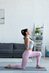 Fototapeta na wymiar side view of brunette woman practicing crescent lunge on knee pose at home
