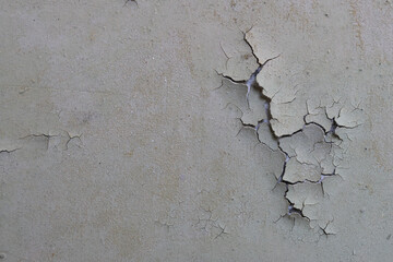 Peeling paint on the wall. Old concrete wall with cracked flaking paint. Weathered rough painted surface with patterns of cracks and peeling. High resolution texture for background and design. Closeup