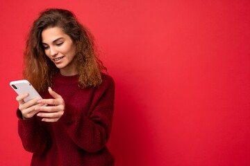 Naklejka premium Beautiful young woman wearing casual clothes standing isolated over background surfing on the internet via phone looking at mobile screen