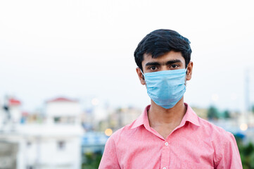 Portrait of young Indian man wearing surgical mask for protection from harmful virus and pollution