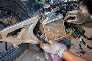 Fototapeta premium Auto motorcycle radiator Being disassembled by the hands of a motorbike mechanic Hands wearing gloves. So soiled cloth.