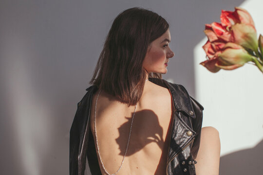 Rear view of a woman wearing a leather jacket back to front with a necklace down her bare back