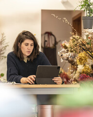 View of a young businesswoman working as florist looking at her laptop, young entrepreneurs concept. - obrazy, fototapety, plakaty