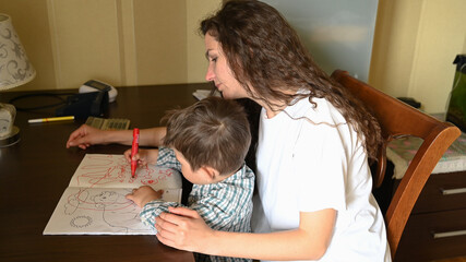 A young mother paints with felt-tip pens with a child