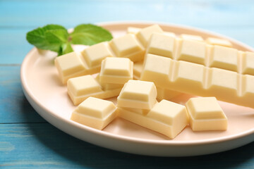 Delicious white chocolate and mint on light blue wooden table, closeup