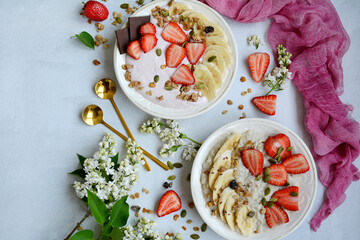 Top view of two plates with muesli, porridge, yogurt and strawberries on a lilac background. Healthy and nutritious breakfast