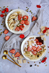 Bowls with yogurt and oatmeal with fresh berries and healthy muesli on a gray background. Top view, vertical