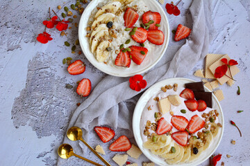 Healthy and tasty breakfast. Oatmeal, yogurt, muesli, strawberries, bananas, waffles on plates on a gray background, top view