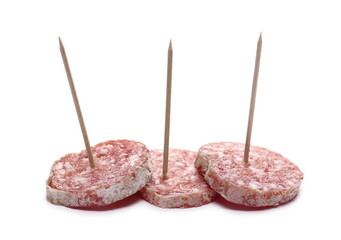 Three fermented semi-hard dried sausage slices served with toothpicks, pig meat isolated on white background