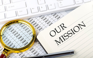 OUR MISSION text on notebook with chart, magnifier,keyboard and pen