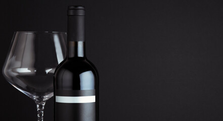 Glass with red wine bottle isolated on black background