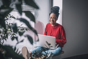 Black woman in red shirt with a laptop