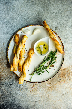 Overhead view of breadsticks (Grissini) on a ceramic plate with olive oil, garlic and rosemary
