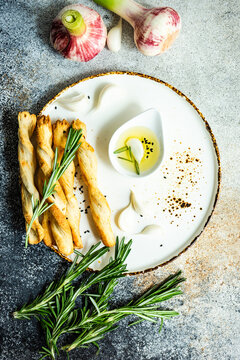 Grissini breadsticks on a plate with olive oil, garlic and rosemary