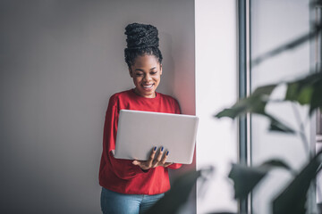 Black woman in red shirt with a laptop working remotely