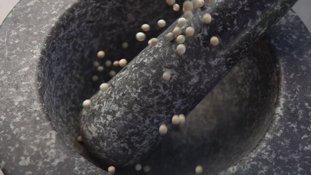 Close-up of spicy exotic white peppercorns falling into the grey stone mortar