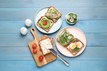 Fototapeta na wymiar Different delicious sandwiches on light blue wooden table, flat lay
