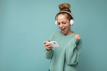 Attractive emotional positive young woman wearing blue sweater isolated over blue background...