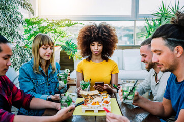 Multiracial group of people using mobile smart phone sitting at bar restaurant - Teenagers and social media interactions on cellphone  - Technology concept with millennials online with smartphones