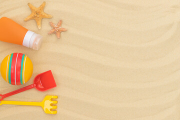 Summer beach background with children's toys sunscreen and starfishes on the sand