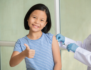 Asian little girl in doctor's office is vaccinated. Syringe with vaccine for covid-19...