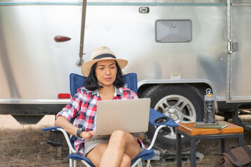 Woman looking at the laptop near the camping . Caravan car Vacation. Family vacation travel,...