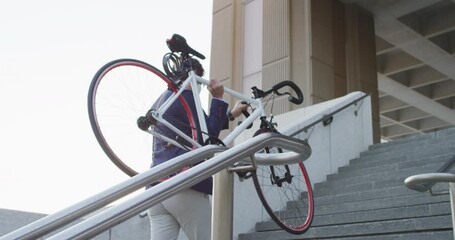 Asian man wearing face mask carrying bicycle while climbing up the stairs at corporate park - Powered by Adobe