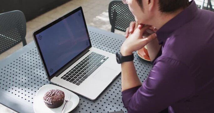Asian man looking at the laptop with copy space while sitting at a cafe