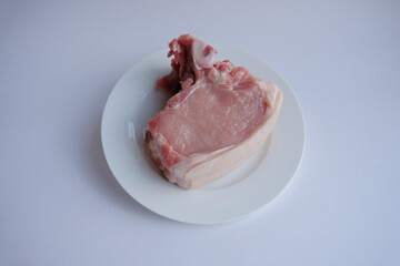 a piece of meat (pork steak) on a white plate. fresh pork meat for barbecue