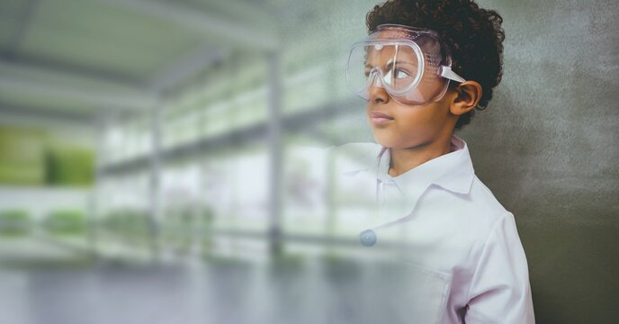 Composition of schoolboy with protective glasses in school laboratory with blurred classroom
