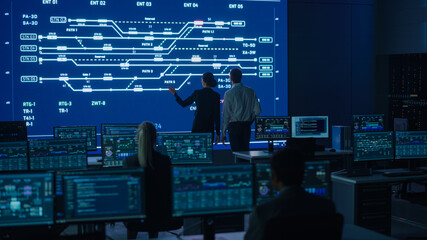 Project Manager and Computer Science Engineer Talking while Using Big Screen Display Showing...