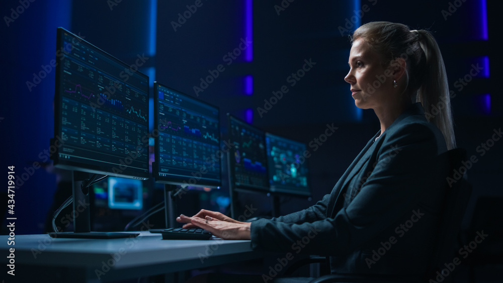 Poster confident female data scientist works on personal computer in big infrastructure control room. stock