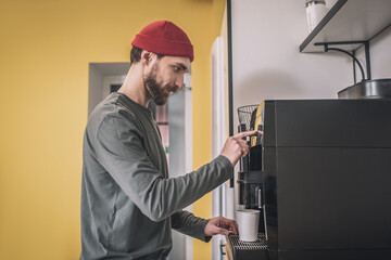 Man in a red hat standing near the coffee machine