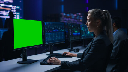 Confident Female Data Scientist Works on Green Chroma Key Screen Computer in Big Infrastructure Control Room. Specialists Use Computers Showing Graphs, Information. Control Room Professional Team