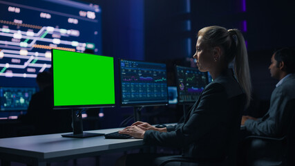 Confident Female Data Scientist Works on Green Chroma Key Screen Computer in Big Infrastructure Control Room. Specialists Use Computers Showing Graphs, Information. Control Room Professional Team