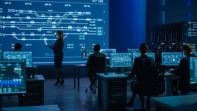 Telecommunications Company System Control and Monitoring Room with Diverse Multicultural Team of Professionals Working on Computers. Big Screen Display Showing Infrastructure Infographics and Data