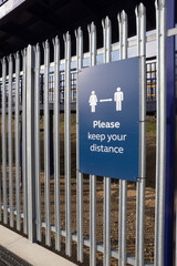 Please keep your Distance sign reminding people to socially distance in blue on a fence
