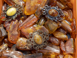 Amazing old Baltic amber brooches lie on yellow and orange amber stones. Amber texture, vintage...