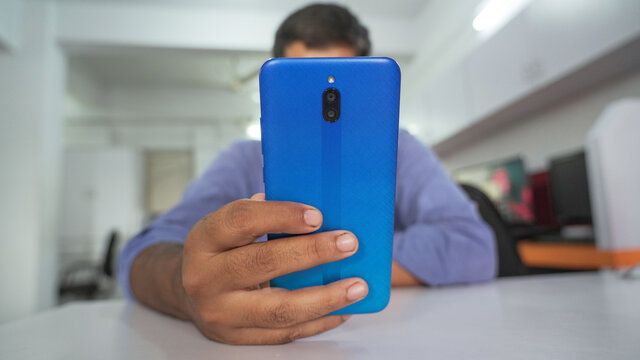 Faceless man using modern smartphone device while sitting at office