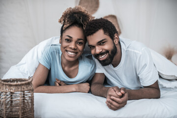 Dark skinned husband and wife lying on bed