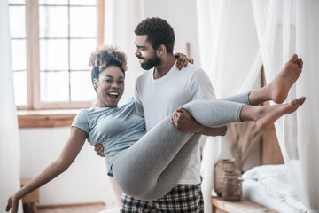 Caring man holding joyful woman in his arms