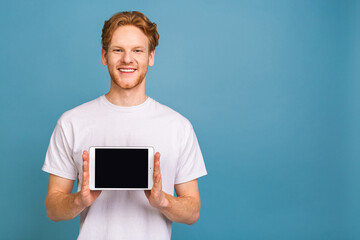 Product presentation. Promotion. Young man holding in hands tablet computer with blank screen, close up. Isolated over blue background.