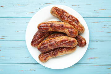 Grilled sausages on white plate on blue background
